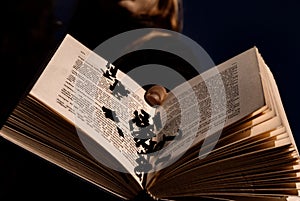 Person holding an open book with letters falling out