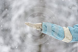 Person holding out a gloved hand to catch the snow