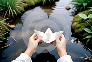 a person holding a paper boat in front of a pond