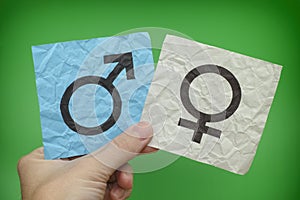 Person holding paper notes with Gender Symbols in his hand