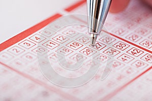 Person holding pen over lottery ticket