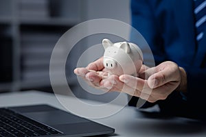 A person is holding a piggy bank, saving money and managing personal finances. Concept of increasing savings and savings by