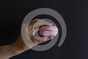 Person holding a pink delicious marshmallow on dark background.