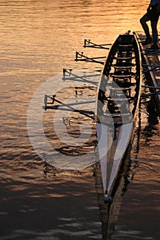 A person holding a row boat along the dock with their foot in the seattle sunrise