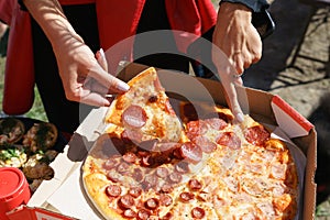 A person is holding a slice pepperoni pizza