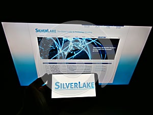 Person holding smartphone with logo of US private equity investment company Silver Lake Technology Management on display.