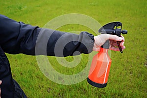 Person holding a spray bottle in hand. Spraying water with spray diffusor. Gardening.