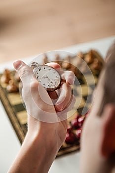 Person Holding Stop Watch Above Chess Board