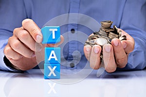 Person Holding Tax Cubic Blocks And Golden Coins