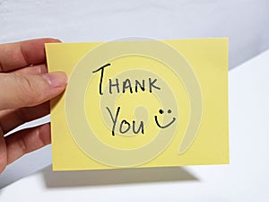 A person holding a Thank You note with a smiling face