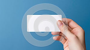 Person is holding up white card in their hand. The card has been placed on top of blue background for contrast and