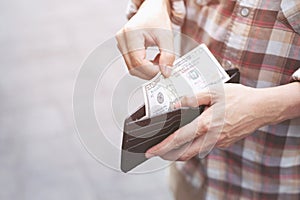 Person holding an wallet in the hands of an man take money