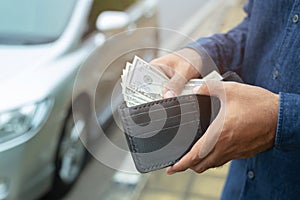 Person holding a wallet in the hands of take money out of pocket stand front car prepare pay by installments - insurance, loan and