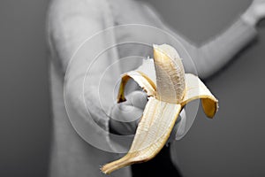 Person holding a yellow banana fruit in hand near black and white background, giving away healthy concept