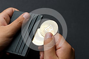 A person holds Bitcoin coins. A businessman puts bitcoin gold coins into a wallet. Bitcoin purchase concept. Bitcoin and wallet. B