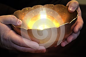 A person holds a magic bowl in his hands, from which a magical light shines