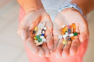 A person holds several medicine pills in the palm of both hands