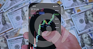 Person holds smartphone and earns easy money on stock trading. Professional trader uses smartphone app to analyze Stock