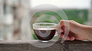 Person holds transparent cup filled with aromatic espresso
