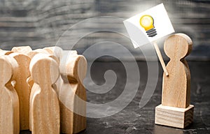 A person with an idea light bulb sign agitates a group of people. The concept of proposing new fresh ideas, finding a solution