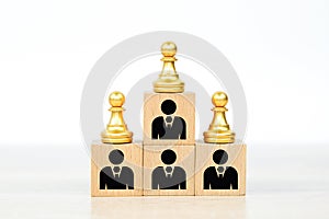 Person individual people icons and chess on wooden toy blocks stacked in pyramid.