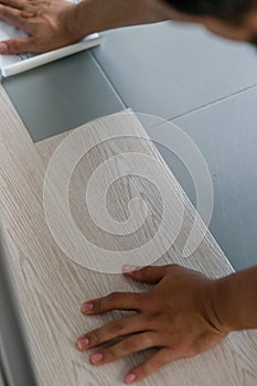 A person installing new vinyl tile floor, a DIY home project