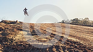 Person, jump and dirt track of professional motorcyclist in the air for trick, stunt or race on outdoor terrain. Expert