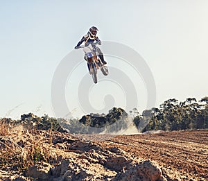 Person, jump and motorbike of professional motorcyclist in the air for trick, stunt or race on outdoor dirt track