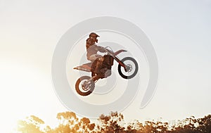 Person, jump and motorcyclist in the air with sunset on mockup for trick, stunt or ramp on outdoor dirt track. Expert