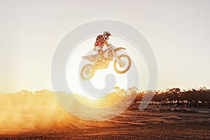 Person, jump and motorcyclist with sunset for trick, stunt or ramp on mockup or outdoor dirt track. Expert rider on