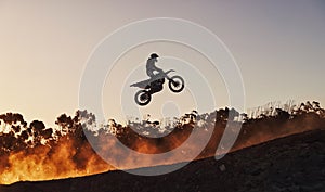 Person, jump and professional motorcyclist in the air on mockup for trick, stunt or ramp on outdoor dirt track. Expert