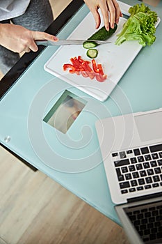 Person with a knife is cutting cucumber