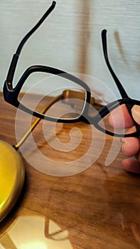 person leaving reading glasses on the wooden bedside table due to fatigue