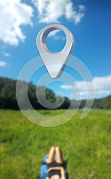 A person lies on a green meadow under a large way point symbol