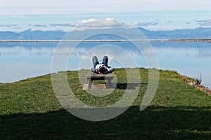 A person lies with their hands clasped behind their head, admiring the view out over the inlet at the old wharf in Motueka photo