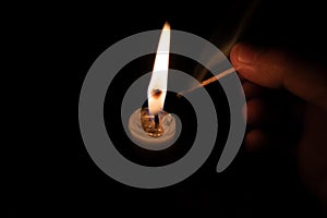 Person lighting a candle with a matchstick. Fingers with extinguished matchstick