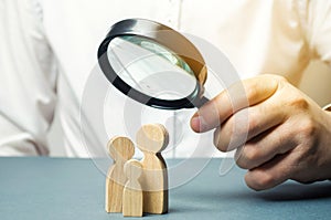 A person looks at family figures through a magnifying glass. The study of family composition, statistics. Birth control