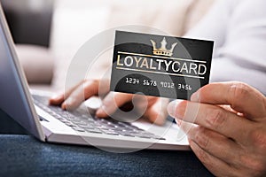Person With Loyalty Card Using Laptop