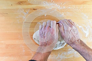 Person making bread in a home kitchen adding ingredients to make the dough and then kneading it by hand