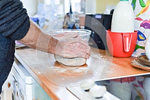 Person making bread in a home kitchen adding ingredients to make the dough and then kneading it by hand