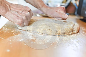 Person making bread in a home kitchen adding ingredients to make the dough and then kneading it by hand