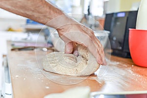 Person making bread in a home kitchen adding ingredients to make the dough and then kneading it by hand