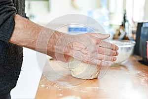 Person making bread in a home kitchen adding ingredients to make the dough and then kneading it by hand