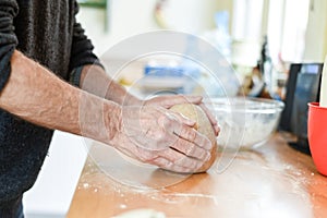 Person making bread in a home kitchen adding ingredients to make the dough and then kneading it by hand