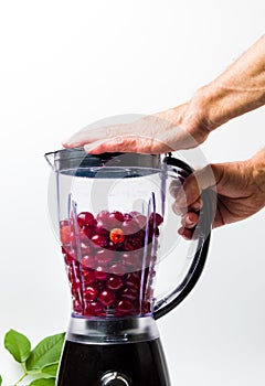 Person making cherry smoothie with a blender