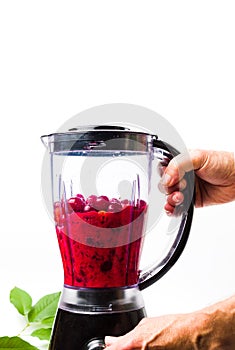 Person making cherry smoothie with a blender