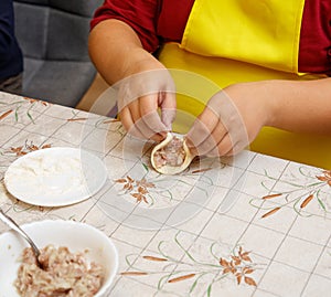 A person is making a dumpling on a table