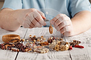 Person making earings from colorful beads and needles