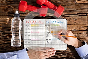 Person Making Exercise Plan On Notebook