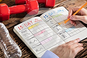 Person Making Exercise Plan On Notebook